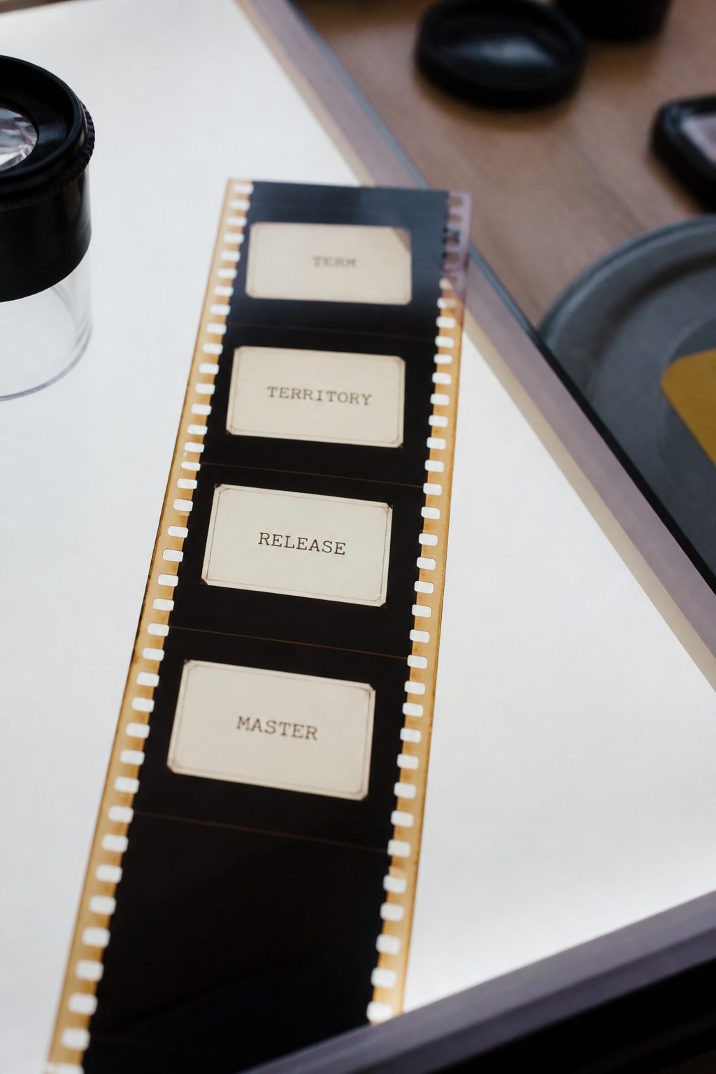 Strip of film frames laid on a light table, each frame carrying a printed label such as term, territory, release and master.